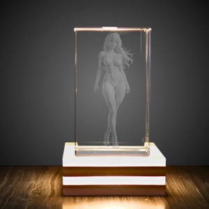 May include: A rectangular clear glass block featuring a laser-etched three-dimensional figure of a standing person with long hair. The glass block is mounted on a square base that emits a bright white light, illuminating the etched figure from below.