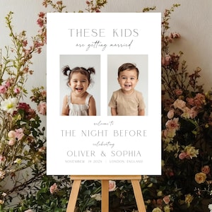 May include: A white wedding sign on a wooden easel, featuring two smiling children's photos. The sign reads "THESE KIDS are getting married" and "welcome to THE NIGHT BEFORE celebrating OLIVER & SOPHIA November 19 2025 LONDON ENGLAND."