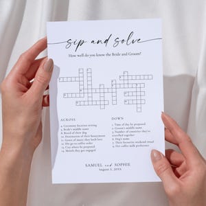 May include: A white paper with a crossword puzzle titled "Sip and Solve" held by hands. The text "How well do you know the Bride and Groom?" is above the puzzle. The names "Samuel and Sophie" and the date "August 3, 2055" are at the bottom.