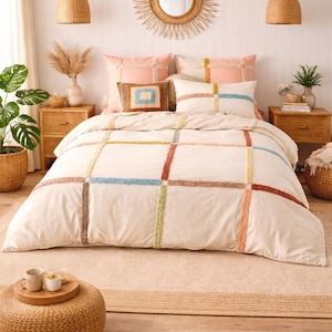 May include: A white ceramic mug with a black handle and the text "But First, Coffee" in a bold, black font. The mug is set against a blurred background, suggesting a cosy setting.