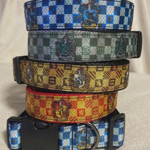 May include: A stack of five dog collars with black plastic buckles. The collars feature various patterns and colors, including blue and white checkered, green and white checkered, gold and brown, and red and gold checkered designs.