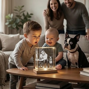 May include: A clear, rectangular photo block illuminated from below, displaying a family portrait. Two young children and a Boston Terrier dog are looking at the block. A family is smiling in the background. The block sits on a wooden table.