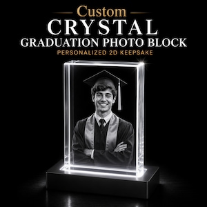 May include: A custom crystal graduation photo block with a black and white image of a graduate in a cap and gown. The block is illuminated on a black base, with the text "Custom Crystal Graduation Photo Block" at the top.