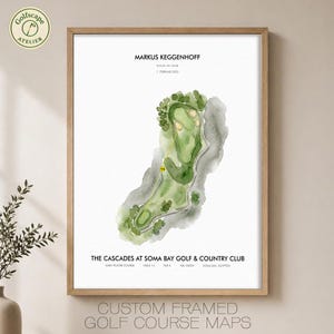 May include: A framed print featuring a watercolor map of a golf course hole. The text reads MARKUS KEGGENHOFF, HOLE-IN-ONE, 1. FEBRUAR 2022, THE CASCADES AT SOMA BAY GOLF & COUNTRY CLUB, GARY PLAYER COURSE, HOLE 14, PAR 3, 186 YARDS, SOMA BAY, EGYPTEN.