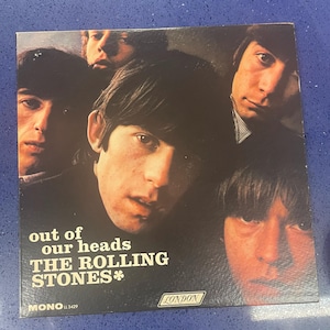 May include: Album cover for "Out of Our Heads" by The Rolling Stones. The cover features a dark background with the faces of the band members. The album title and band name are in white text, with the London Records logo.