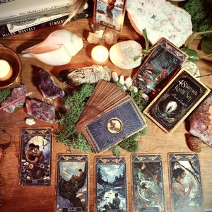 May include: A collection of tarot cards, crystals, candles, and other mystical items arranged on a wooden surface. The cards feature detailed illustrations, and the scene is illuminated by candlelight, creating a spiritual atmosphere.