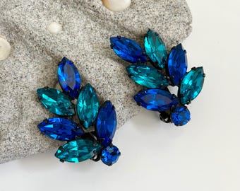 Pendientes de clip de estilo Regencia vintage en azul pavo real con pedrería, y racimos de hojas de metal negro lacado.