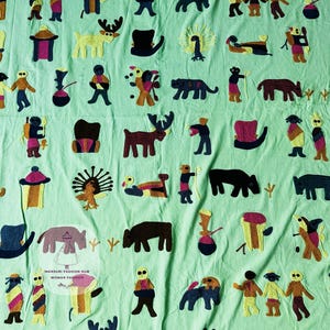 Könnte beinhalten: Hellgrüner Stoff mit gestickten Figuren von Menschen, Tieren und Hüten. Das Design umfasst Hirsche, Tiger und Händchen haltende Menschen. Der Text "MANSURI FASHION HUB WOMAN FASHION" ist sichtbar.