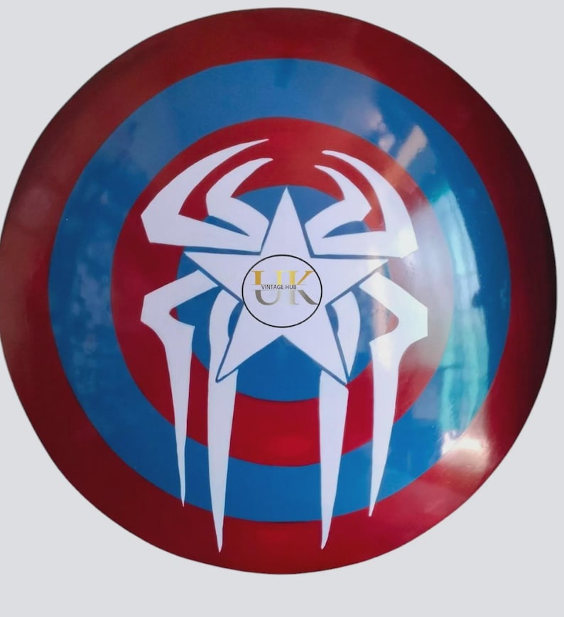 May include: A circular shield with a red, white, and blue design. The shield features a central white star with a spider-like design and the text "UK VINTAGE HUB". The shield has a glossy finish.