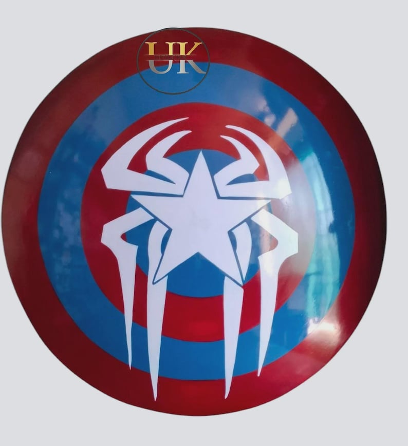 May include: A circular shield in red, white, and blue. It has concentric rings of red and blue, with a white star and a white spider design in the center. The letters "UK" are visible at the top of the shield.