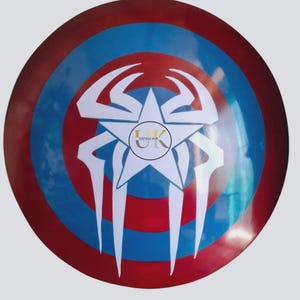 May include: A circular shield in red, white, and blue. It has a white star and a spider web design. The centre of the shield has the text "VINTAGE HUB" in a circle. A decorative item.
