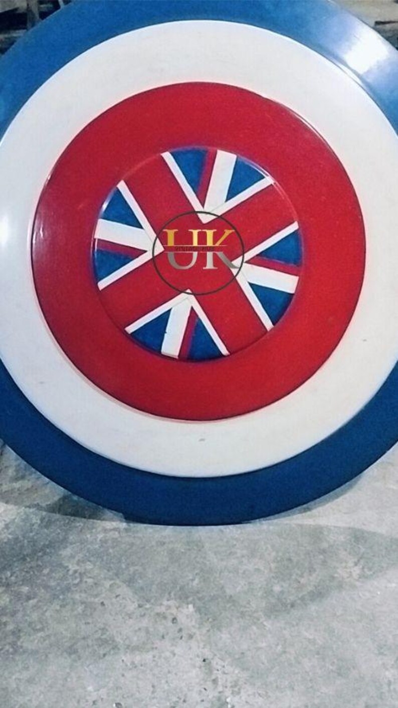 May include: A round shield with a blue, white, and red color scheme. The shield features a central red circle with a white and blue starburst design. The outer ring is white, and the edge is blue.