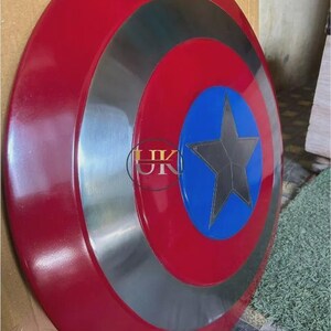 K&ouml;nnte beinhalten: Ein kreisf&ouml;rmiger Schild mit einem gl&auml;nzenden roten Au&szlig;enring, einem metallisch silbernen Mittelring und einem leuchtend blauen Mittelkreis. Ein dunkelgrauer f&uuml;nfzackiger Stern befindet sich in der Mitte des blauen Kreises. Die Buchstaben UK sind sichtbar.