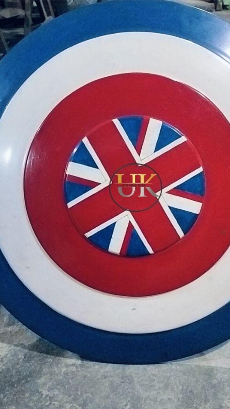 May include: A round shield with a patriotic design. The shield features concentric circles in blue, white, and red. The center showcases a red circle with a Union Jack design, incorporating blue, white, and red elements. The shield has a glossy finish.