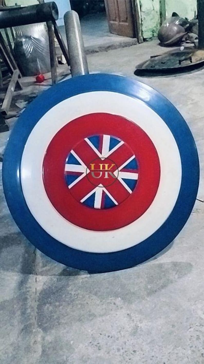 May include: A round shield with a blue outer ring, a white middle ring, and a red center. The center features a Union Jack design with the letters "UK" in the middle. The shield is likely made of metal.