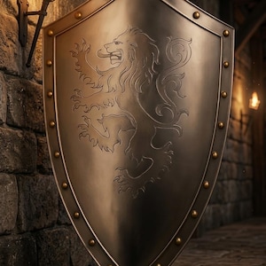 May include: A metallic heater-style shield featuring a polished silver finish and a central engraved lion rampant design. The shield is bordered by a raised rim accented with evenly spaced brass-colored rivets along the entire outer edge.