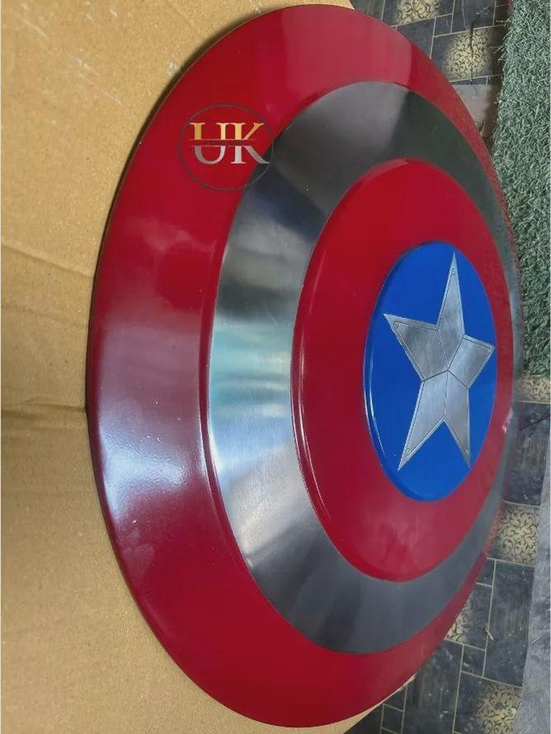 K&ouml;nnte beinhalten: Ein kreisf&ouml;rmiger Schild mit einem gl&auml;nzend roten Au&szlig;enring, einem metallisch silbernen Mittelring und einem blauen Mittelkreis mit einem markanten silbernen f&uuml;nfzackigen Stern. Der Text "UK" ist in roter Schrift oben links aufgedruckt.