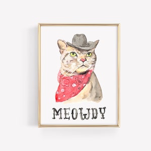 Può includere: Dipinto ad acquerello di un gatto con cappello da cowboy e bandana rossa. Il gatto ha gli occhi gialli e un'espressione seria. La parola "MEOWDY" è scritta in nero sotto.