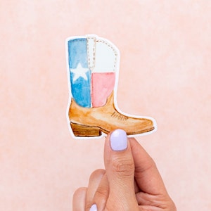 May include: A watercolor illustration of a brown cowboy boot with a Texas flag design. The boot is blue, white, and red with a white star on the blue section.