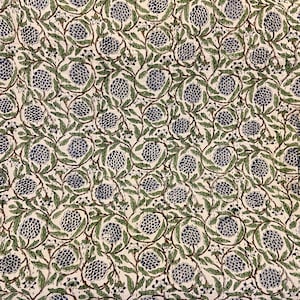 May include: A white fabric with a repeating pattern of blue floral clusters and green leaves connected by brown stems. The design is densely packed, creating a textured appearance. The fabric is likely used for home decor.