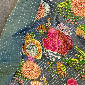 May include: A floral patterned quilt with a dark gray background. The quilt features large, colorful flowers in shades of orange, pink, yellow, and green. The quilt is hand-stitched with white thread, and the edges are a solid teal color.