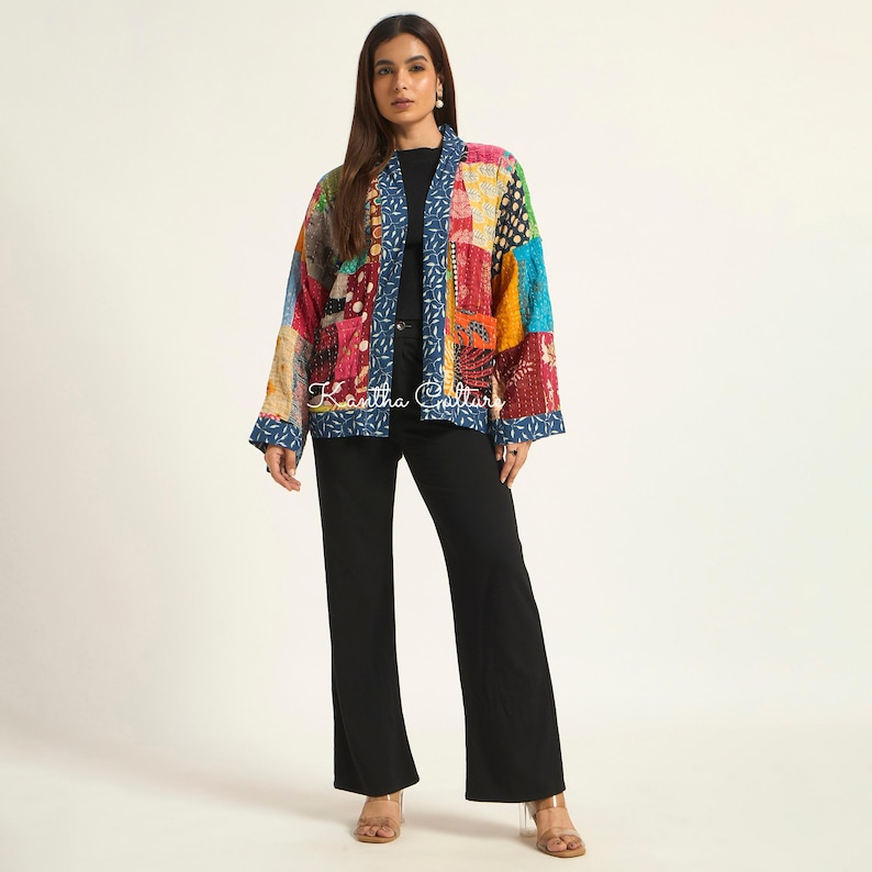 Puede incluir: Una chaqueta de manga larga con un dise&ntilde;o de patchwork que presenta varios patrones y texturas coloridas. La chaqueta tiene un borde azul con un estampado de hojas blancas a lo largo de la abertura frontal y los pu&ntilde;os. El texto Kantha Culture es visible.