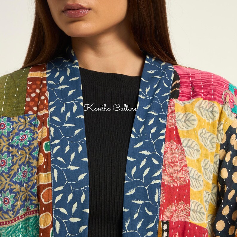 Puede incluir: Una chaqueta acolchada con un dise&ntilde;o de patchwork que presenta varios patrones coloridos, incluyendo motivos florales, de hojas y de lunares. La prenda tiene un cuello azul con un estampado de hojas blancas y el texto Kantha Culture en blanco.