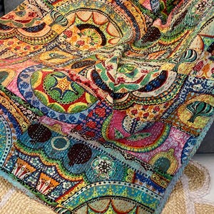 May include: A colorful, patterned quilt with a vibrant mix of hues including pink, blue, green, and yellow. The quilt features intricate circular designs and detailed stitching, creating a rich, textured appearance. The overall theme is bohemian and artistic.