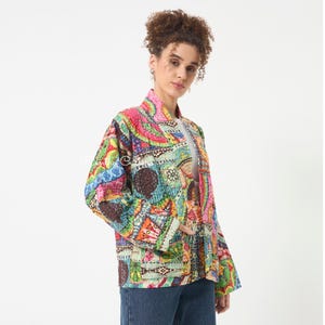 Pu&ograve; includere: Una giacca trapuntata a maniche lunghe caratterizzata da un vivace motivo patchwork multicolore con cuciture intricate. La giacca presenta un colletto rialzato, un design aperto sul davanti e due tasche visibili, mostrando una variet&agrave; di motivi geometrici e floreali nei toni del rosa, verde, blu e giallo.