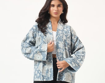 Könnte beinhalten: Eine gesteppte Jacke mit einem blau-weißen Blumenmuster im Blockdruck. Das Kleidungsstück hat ein offenes Vorderteil, lange, weite Ärmel und einen geraden Saum. Der Stoff weist durchgehend eine sichtbare, gesteppte Textur auf.