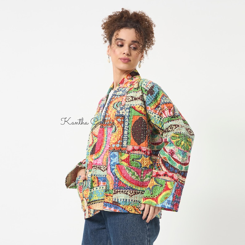 Pu&ograve; includere: Una giacca a maniche lunghe caratterizzata da un vivace motivo patchwork multicolore con intricate cuciture kantha. Il capo presenta un colletto strutturato, apertura frontale e tasche laterali. Il testo Kantha Culture &egrave; visibile a sinistra.