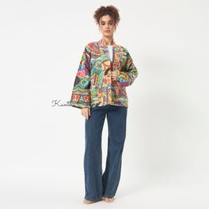 Pu&ograve; includere: Una giacca a maniche lunghe aperta sul davanti con un vivace motivo patchwork multicolore e dettagli di cucitura intricati. Il capo &egrave; abbinato a jeans in denim blu scuro a gamba larga. Il testo Kantha Quilt &egrave; visibile sul lato sinistro.