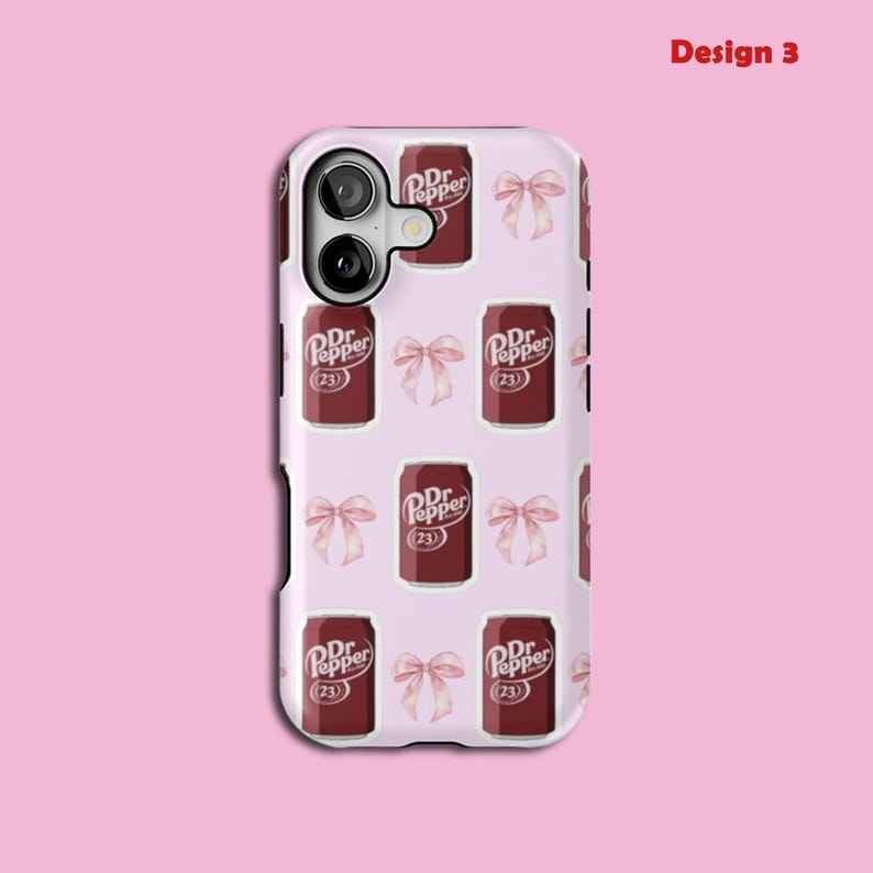 May include: A phone case featuring a repeating pattern of Dr. Pepper cans and pink bows on a pale pink backdrop. The Dr. Pepper cans are dark red with white text and the number 23. The words "Design 3" are in the upper right corner.
