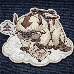 May include: An embroidered patch featuring a cream-colored, six-legged bison creature with a brown arrow on its head. The creature stands on a white cloud, holding a scroll labeled ADVENTURE, with a thought bubble showing a temple icon above.