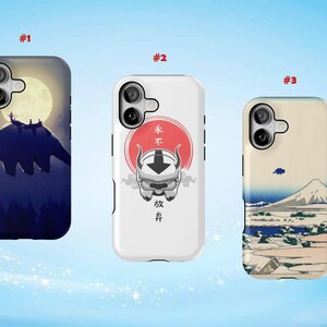 May include: Three phone cases with unique designs. The first case features a silhouette of a flying bison against a moonlit sky. The second case has a character illustration with Japanese text. The third case depicts a mountain landscape.