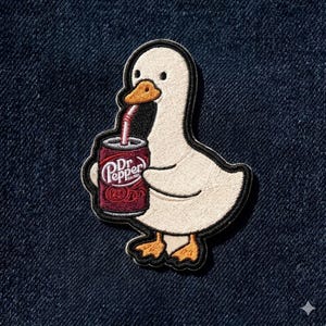 May include: Embroidered patch featuring a white goose with an orange beak and feet, holding a Dr. Pepper can with a red straw. The patch has a black outline and is set against a dark blue denim background.
