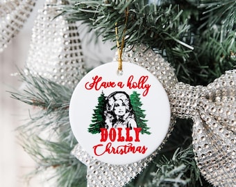 May include: White ceramic Christmas ornament with the text "Have a holly DOLLY Christmas" in red script. The ornament features a black and white portrait of a woman with two green Christmas trees.