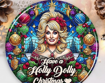 May include: Round Christmas ornament featuring a portrait of a woman with blonde hair, surrounded by a stained-glass design. The ornament has the text "Have a Holly Dolly Christmas" in white script. Ornaments and holly berries decorate the border.