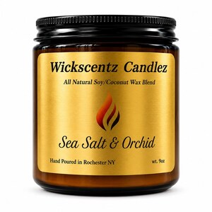 May include: A 9oz amber glass jar candle with a black screw-top lid. The gold label features the text Wickscentz Candlez, All Natural Soy/Coconut Wax Blend, Sea Salt & Orchid, and Hand Poured in Rochester NY, with a central flame graphic.