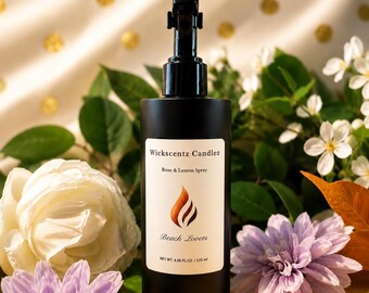 May include: A matte black cylindrical spray bottle with a black trigger nozzle. The white label features the text Wickscentz Candlez, Rose & Lemon Spray, Beach Lovers, and NET WT. 4.06 FL.OZ. / 120 ml, along with a stylised orange flame graphic.
