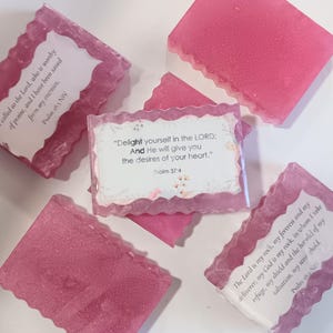 Op de afbeelding: Roze, rechthoekige zepen met een glitterafwerking en geschulpte randen. Sommige zepen hebben witte labels met bijbelteksten. De tekst bevat "Verheug u in de HEERE" en "De HEERE is mijn rots".