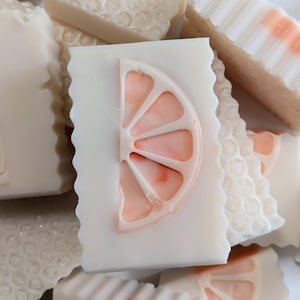 Puede incluir: Una taza de cerámica blanca con un asa negra y el texto "But First, Coffee" en un estilo manuscrito. La taza está sobre una superficie blanca. La taza mide aproximadamente 10 cm de alto.