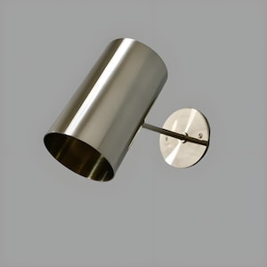 Bring timeless elegance to your interior with this handcrafted Mid-Century Brass Wall Sconce. Inspired by 1950s design, it features clean lines, a satin nickel finish, and soft ambient lighting—perfect for bedrooms, hallways, or reading nooks. Made from solid brass and built to last, this sconce blends vintage charm with modern craftsmanship. Hardwired with E12/E14 socket. Bulb not included.