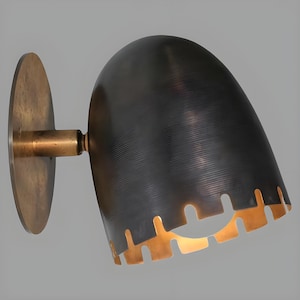 May include: A wall-mounted sconce with a dark, curved shade and a circular mounting plate. The shade has a textured surface and a scalloped edge with a warm, golden interior. The fixture is made of metal and has a vintage aesthetic.