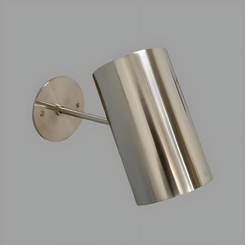 Bring timeless elegance to your interior with this handcrafted Mid-Century Brass Wall Sconce. Inspired by 1950s design, it features clean lines, a satin nickel finish, and soft ambient lighting—perfect for bedrooms, hallways, or reading nooks. Made from solid brass and built to last, this sconce blends vintage charm with modern craftsmanship. Hardwired with E12/E14 socket. Bulb not included.