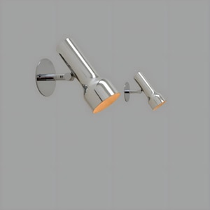 Op de afbeelding: Twee verchroomde wandspots. De grotere spot is naar beneden gericht, met een ronde basis en een cilindrisch lichaam. De kleinere spot heeft een vergelijkbaar ontwerp. Beide hebben een warme, oranje gloed.