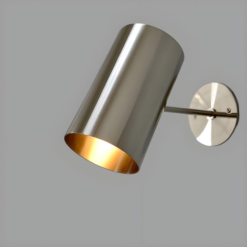 Bring timeless elegance to your interior with this handcrafted Mid-Century Brass Wall Sconce. Inspired by 1950s design, it features clean lines, a satin nickel finish, and soft ambient lighting—perfect for bedrooms, hallways, or reading nooks. Made from solid brass and built to last, this sconce blends vintage charm with modern craftsmanship. Hardwired with E12/E14 socket. Bulb not included.