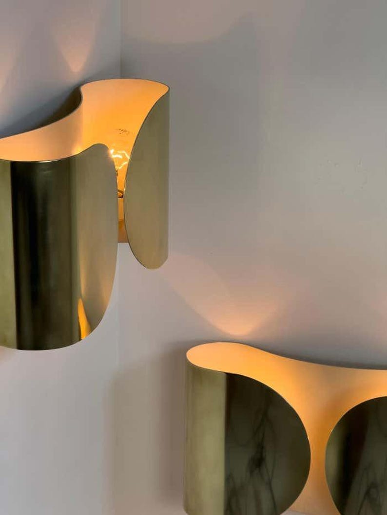Inspired by iconic mid-century Italian design, the Foglio Wall Sconce brings refined elegance and architectural presence to any interior. Crafted from solid brass with a luxurious Italian gold finish, this sculptural sconce evokes the graceful fold of paper—its name, Foglio, meaning “sheet” in Italian.