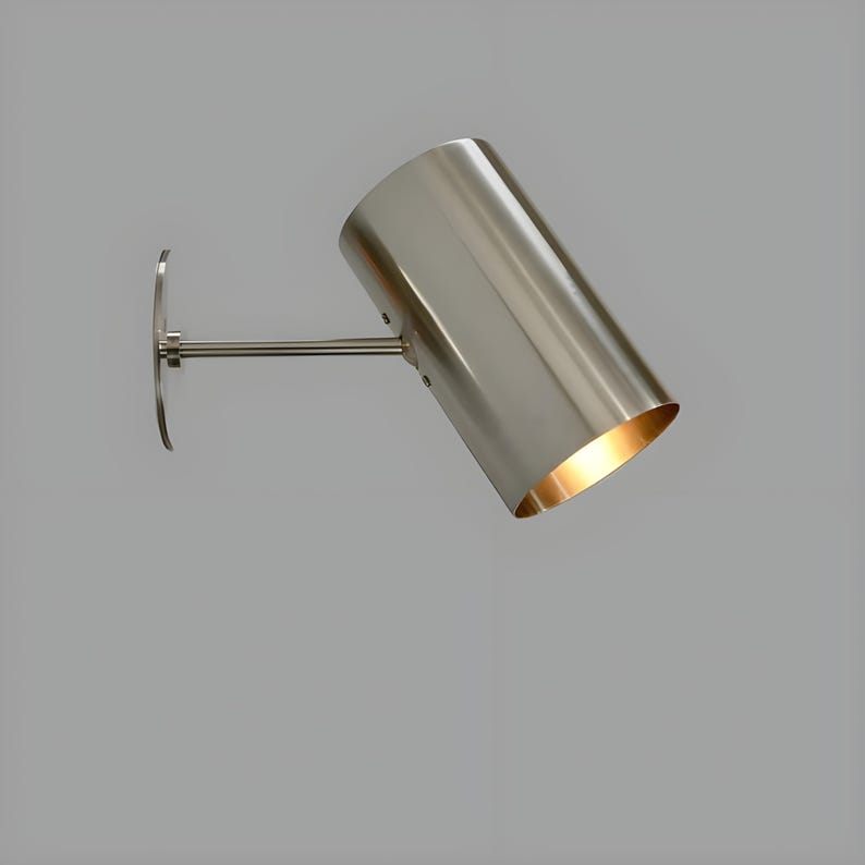 Bring timeless elegance to your interior with this handcrafted Mid-Century Brass Wall Sconce. Inspired by 1950s design, it features clean lines, a satin nickel finish, and soft ambient lighting—perfect for bedrooms, hallways, or reading nooks. Made from solid brass and built to last, this sconce blends vintage charm with modern craftsmanship. Hardwired with E12/E14 socket. Bulb not included.