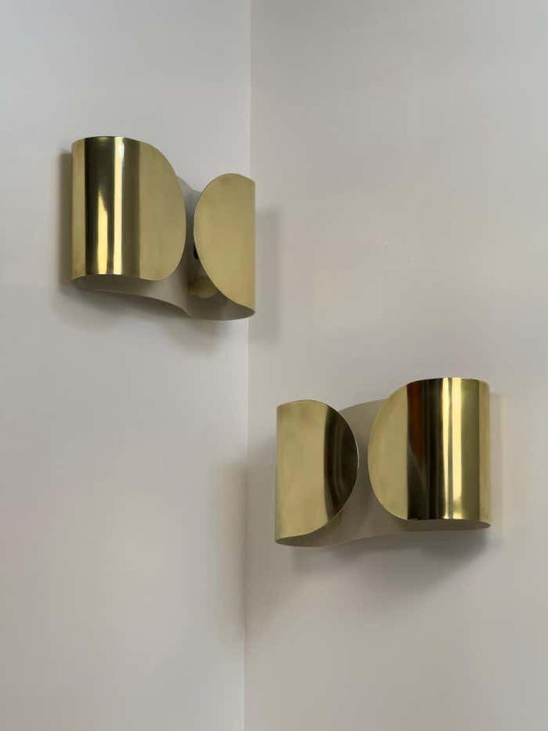 Inspired by iconic mid-century Italian design, the Foglio Wall Sconce brings refined elegance and architectural presence to any interior. Crafted from solid brass with a luxurious Italian gold finish, this sculptural sconce evokes the graceful fold of paper—its name, Foglio, meaning “sheet” in Italian.